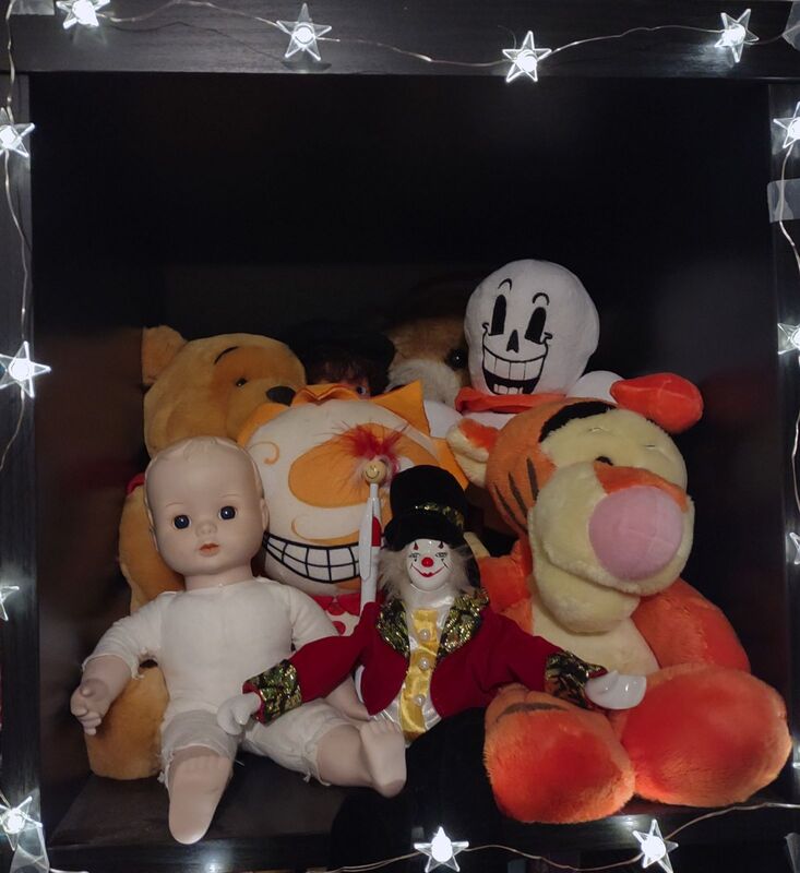 Peppy surrounded by stuffed animals, including a baby doll, clown, Tigger, Pooh, Sundrop, Papyrus, and a teddy bear